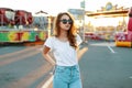 Stylish redhead modern hipster young woman in trendy sunglasses in a white t-shirt in vintage jeans posing Royalty Free Stock Photo