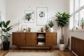 Stylish and retro composition of living room with design wooden retro commode, clock, a lot of plants and elegant accessories. Mod