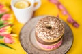 A stylish retro dish with delicious chocolate donuts, a cup of tea, beautiful tulips and a tailor`s meter on a yellow