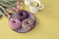 Stylish retro dish with delicious chocolate donuts, a cup of tea and beautiful tulips on yellow background.