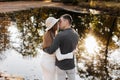 Stylish romantic young loving couple embracing and kissing by the pond at autumn park. Happy woman in hat and man Royalty Free Stock Photo