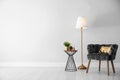 Stylish room interior with  armchair, floor lamp near light wall, space for text Royalty Free Stock Photo