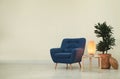 Stylish room interior with comfortable armchair and plant near beige wall Royalty Free Stock Photo