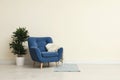 Stylish room interior with comfortable armchair and plant near beige wall Royalty Free Stock Photo