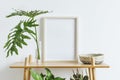 Stylish room interior with mock up photo frame on the brown bamboo shelf with beautiful plants in different designed pots.