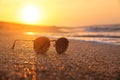 Stylish round sunglasses lie on the wet sand of the sea beach in the rays of the setting sun. Sunset and sunglasses. Sea Royalty Free Stock Photo