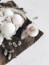 Stylish rural Easter still life. Natural eggs, feathers, willow branches on cloth on rustic table