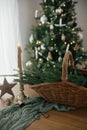 Stylish rustic basket with fir branches, vintage candle and wooden star on table against festive decorated christmas tree in Royalty Free Stock Photo