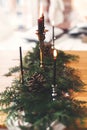 Stylish rustic christmas arrangement for festive dinner. Fir branches with pine cones and vintage candlestick with burning black Royalty Free Stock Photo
