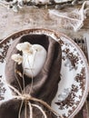 Stylish rustic Easter table setting. Natural egg, napkin, flowers, vintage plate, cutlery, feathers