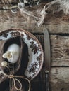 Stylish rustic Easter table setting. Natural egg, napkin, flowers, vintage plate, cutlery, feathers