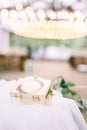 Stylish rustic wooden box for wedding rings filled with moss on the table, restaurant tent outdoors on the background Royalty Free Stock Photo