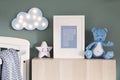 Stylish scandi childroom with wooden mock up photo frame, wooden toys, boxes, blocks and accessories Bright and sunny interior