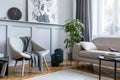 Stylish scandinavian home interior of living room with design gray sofa, armchair and personal accessories.