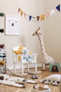 Stylish scandinavian interior of child room with natural toys, hanging decoration, design furniture, plush animals, teddy bears. Royalty Free Stock Photo