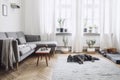 Stylish scandinavian interior of living room with small design table ,sofa, lamp and shelfs. White walls, plants on the windowsill Royalty Free Stock Photo