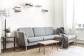 Stylish scandinavian interior of living room with small design table ,sofa, lamp and shelfs. White walls, plants on the windowsill Royalty Free Stock Photo