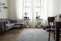 Stylish scandinavian interior of living room with small design table ,sofa, lamp and shelfs. White walls, plants on the windowsill Royalty Free Stock Photo