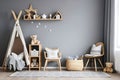 Stylish scandinavian newborn baby room with toys, children's chair, natural basket with teddy bear and small shelf Royalty Free Stock Photo