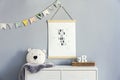 Stylish scandinavian nursery interior with hanging mock up poster, natural toys, teddy bears, children`s accessories and design Royalty Free Stock Photo