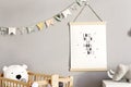 Stylish scandinavian nursery interior with hanging mock up poster, natural toys, teddy bears, children`s accessories and design Royalty Free Stock Photo