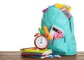 Stylish schoolbag with different stationary and alarm clock on wooden table Royalty Free Stock Photo