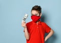 Stylish schoolboy in red medical mask and shirt stands keeping one hand on waist showing crumpled hundred dollar banknote Royalty Free Stock Photo