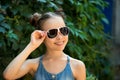 Stylish seasonal portrait of smiling girl in sunglasses front of green leaves background. Summer season. Copytext Royalty Free Stock Photo