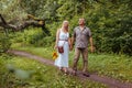 Stylish senior family couple walking outdoors in summer forest. Elderly people holding hands. Woman carries flowers Royalty Free Stock Photo