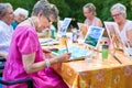 Stylish senior lady painting in art class with friends from her care home for the aged copying a painting with water colors.