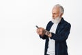 Stylish senior man texting message on smartphone. Old guy with tattoos and beard messaging, reading mobile phone screen Royalty Free Stock Photo