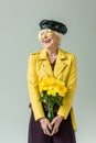 stylish senior woman in yellow leather jacket with bouquet of yellow flowers, Royalty Free Stock Photo