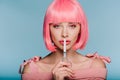 Stylish sensual girl in pink wig showing silence symbol with scissors isolated