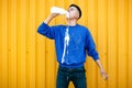 Stylish serious guy in a blue sweater, drinks and spills milk or