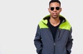 African American man wearing round mirror sunglasses and sporty hoodie, looking to the camera and posing over white studio wall Royalty Free Stock Photo