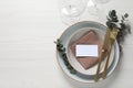 Stylish setting with cutlery, eucalyptus leaves and blank card on white wooden table, flat lay. Space for text Royalty Free Stock Photo