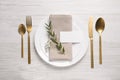 Stylish setting with cutlery, eucalyptus leaves and blank card on white wooden table, flat lay. Space for text Royalty Free Stock Photo