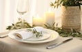 Stylish setting wedding table with place card with olive branch and eucalyptus leaves on white tablecloth Royalty Free Stock Photo