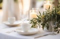 Stylish setting wedding table with place card with olive branch and eucalyptus leaves on white tablecloth Royalty Free Stock Photo