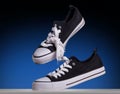Shot a pair of classic black and white sneakers levitating in air with tie their laces on a dark blu background with copy Royalty Free Stock Photo