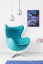 Stylish silver lamps above blue egg chair in modern living room interior with cosmos graphic on the wall, real photo Royalty Free Stock Photo