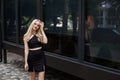 A stylish slender girl with blond long hair and a beautiful smile walks along the city street Royalty Free Stock Photo