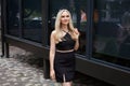 A stylish slender girl with blond long hair and a beautiful smile walks along the city street Royalty Free Stock Photo