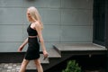 A stylish slender girl with blond long hair and a beautiful smile walks along the city street Royalty Free Stock Photo