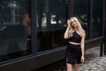 A stylish slender girl with blond long hair and a beautiful smile walks along the city street Royalty Free Stock Photo