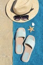 Stylish slippers, straw hat, sunglasses and blue towel on sand, flat lay. Beach accessories Royalty Free Stock Photo