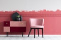 Small pastel pink chair next to trendy pink and burgundy commode