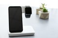 Stylish smart watch and phone charging with wireless pad on grey table Royalty Free Stock Photo