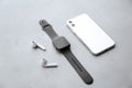 Stylish smart watch, phone and earphones on grey stone table