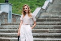 A stylish smiling girl with fashionable makeup and hairstyle, in white trousers and a beige top Royalty Free Stock Photo